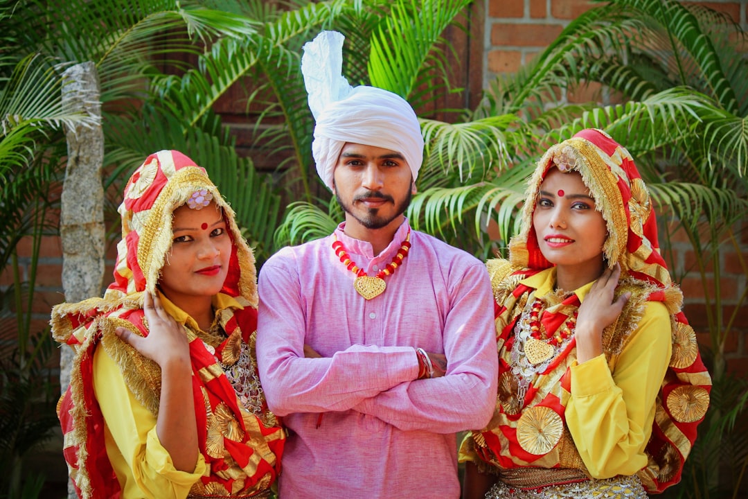 man standing in between two women beside green palm plants, Haryana folk dance</p>
<p></p>
<p>Phaag, Ghoomer, Loor, and Dhamal