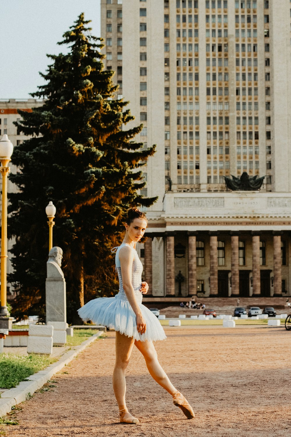 ballerina standing on pathway near buildings