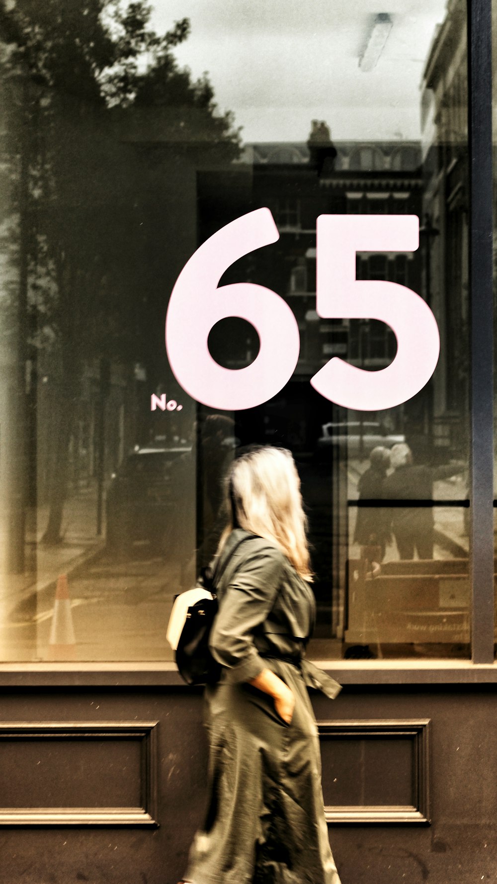 a woman walking past a window with a sign in the window