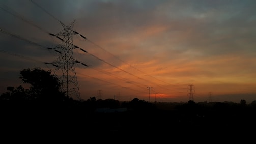 Power transmission towers against a sunset sky.