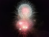 Bright and colorful fireworks burst against a dark night sky, with vibrant streaks of red, white, and blue creating an explosive display.