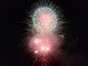 Bright and colorful fireworks burst against a dark night sky, with vibrant streaks of red, white, and blue creating an explosive display.