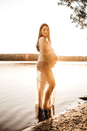 pregnant woman standing on body of water