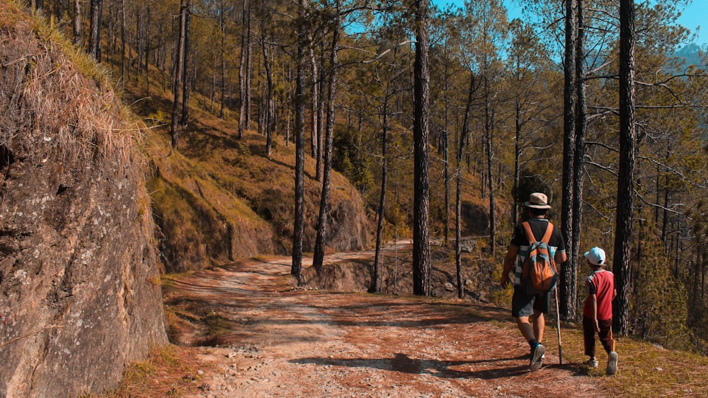 2 person walking on trail by trees during daytime