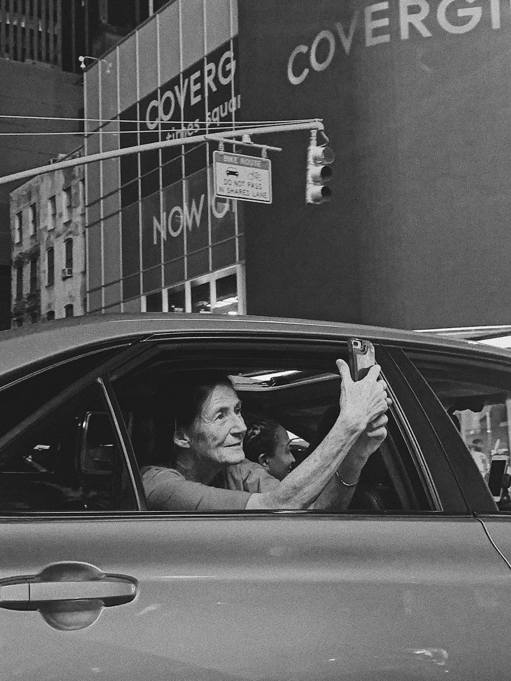 grayscale photography of woman making selfie while sitting inside vehicle