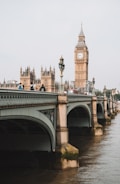 people on bridge near Queen Elizabeth tower under gray skies