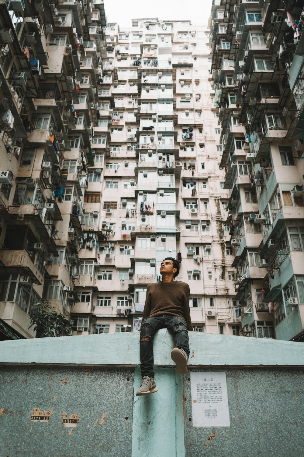 man sitting near concrete building at daytime