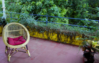 A stylish wicker patio chair set on a sunlit balcony with lush greenery around.