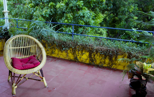 A stylish wicker patio chair set on a sunlit balcony with lush greenery around.