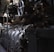 A complex array of industrial machinery and pipes with a large valve wheel dominates the scene. The machinery appears metallic and rugged, with various interconnected components.