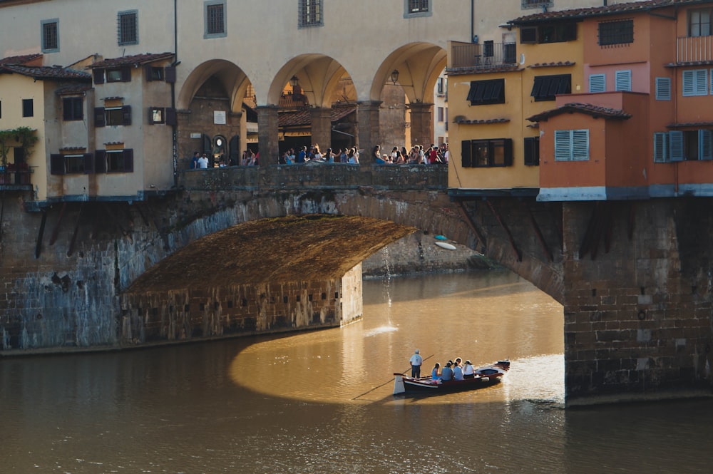 men riding a boat under a concrete bridge