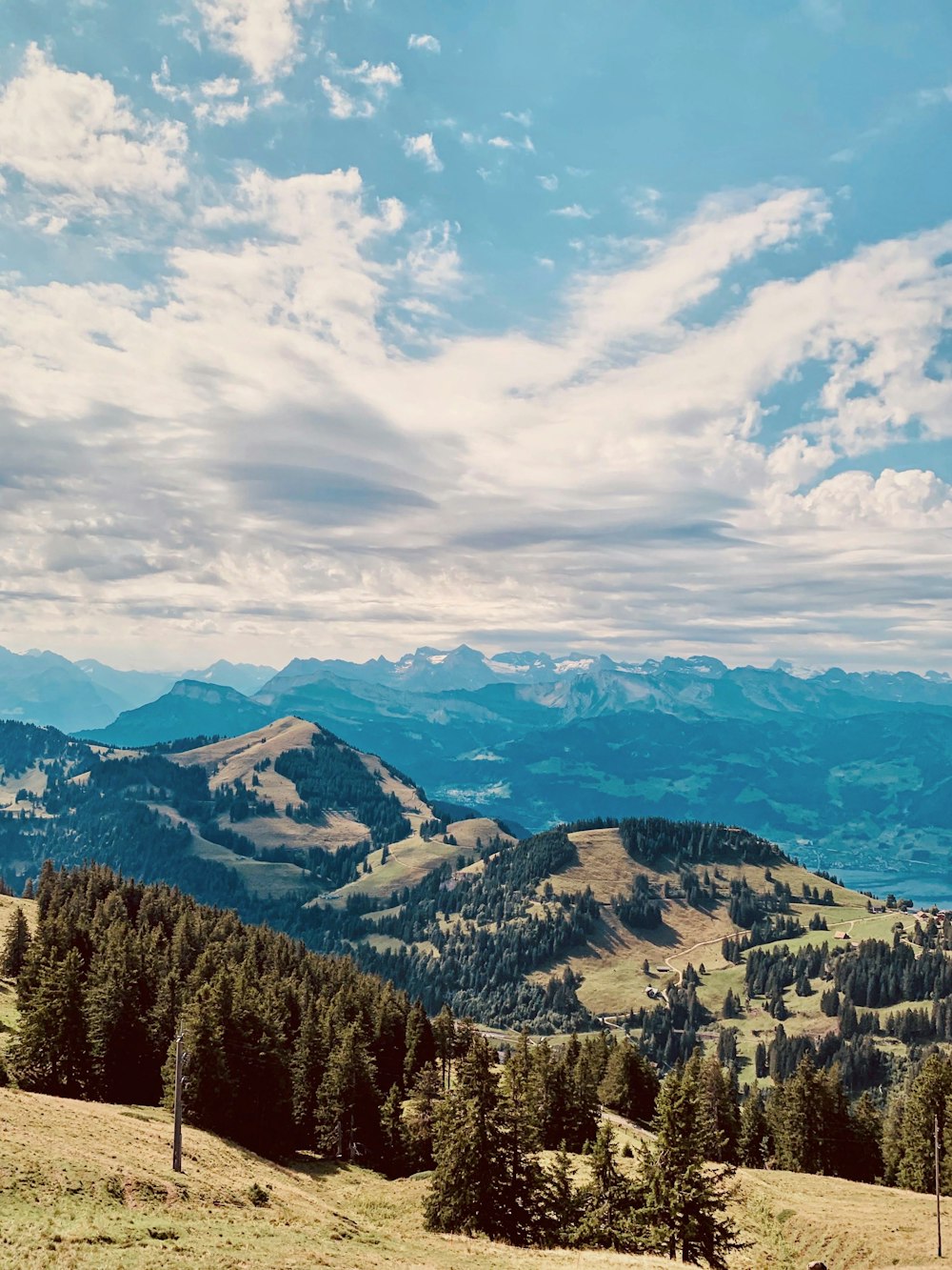 Fotografia aerea della montagna di osservazione del campo verde sotto i cieli bianchi e blu durante il giorno