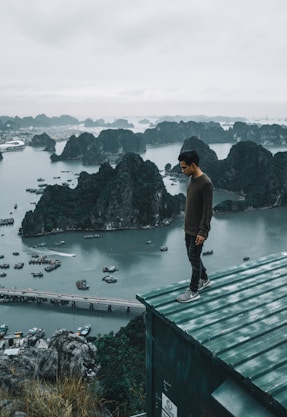 man wearing gray sweater standing on rooftop