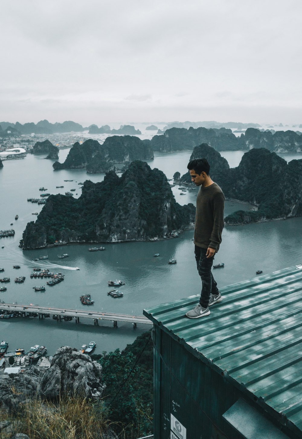 man wearing gray sweater standing on rooftop