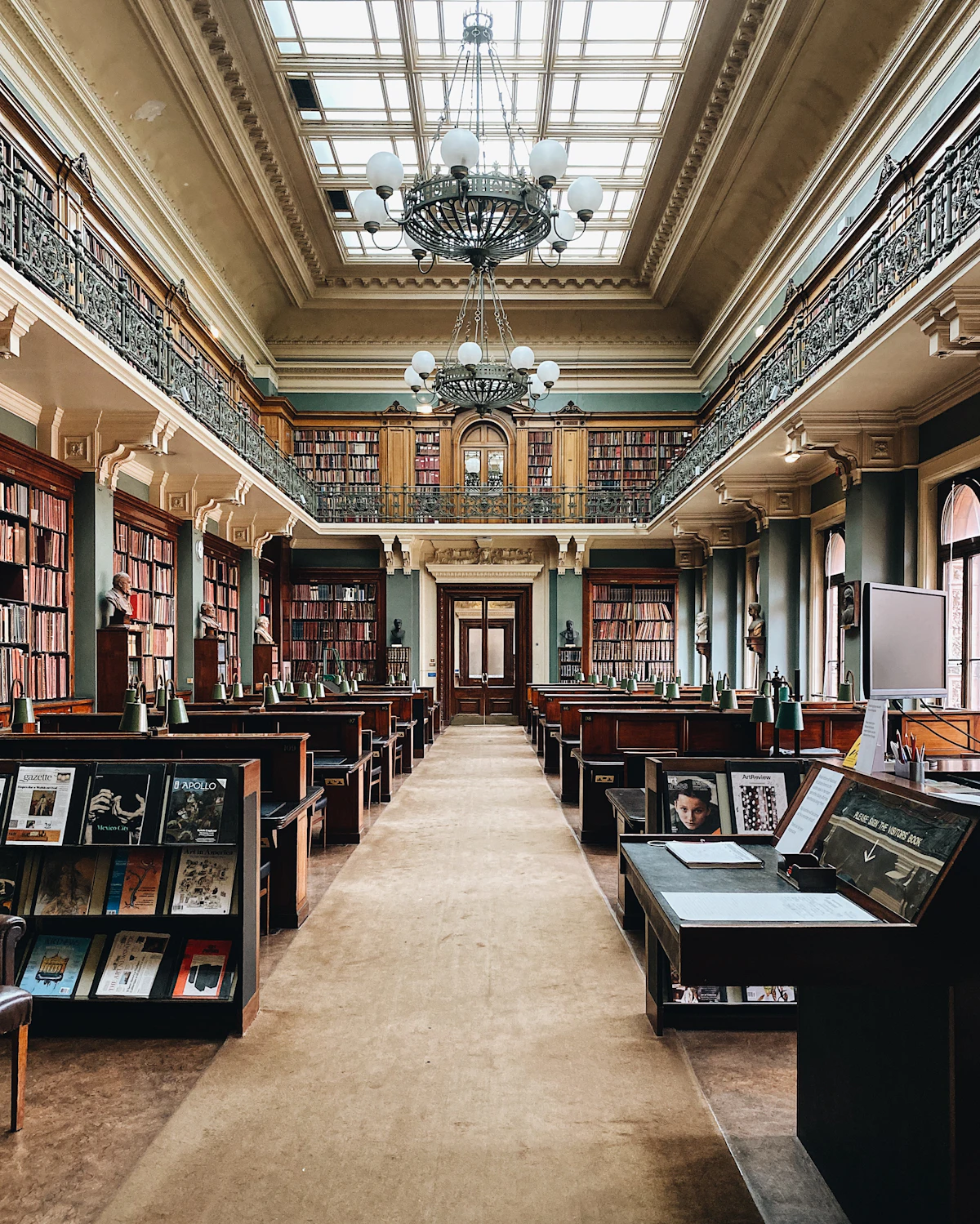 Sala de leitura com mesas compridas e candeeiros