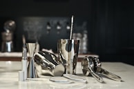 Close-up of a rolling bar cart’s polished wood surface with cocktail tools and a shaker mid-pour.