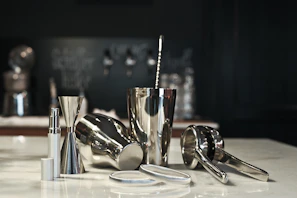 Sleek matte black bar tools resting beside a crystal glass filled with a colorful cocktail.