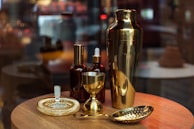 An elegant cocktail shaker mid-pour with flavvafull mixer blending into a glass, surrounded by bar tools on a dark marble surface.