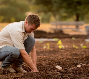 man in white shirt planting at daytime