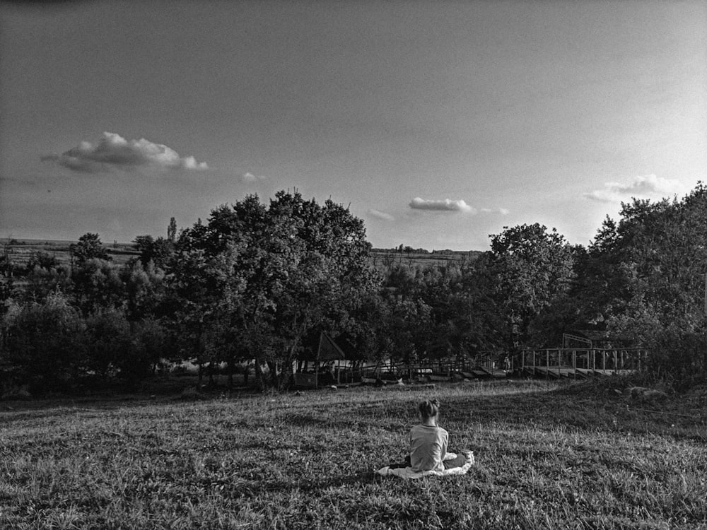 person sitting on grass grayscale photography