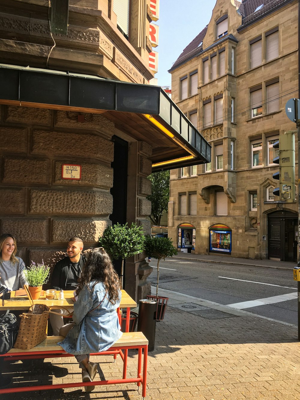 two women and one man sitting on bench outside store