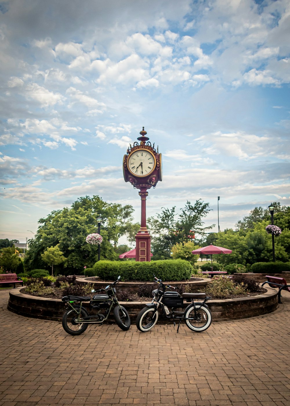 two standard motorcycles parked near a tower clock