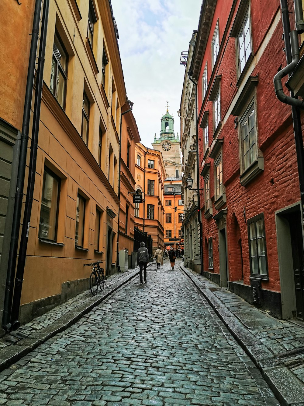 two people walking down a cobblestone street