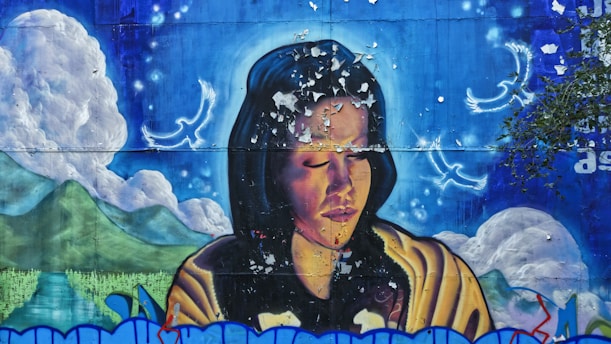 A mural depicting a person with closed eyes, surrounded by celestial imagery including glowing birds and a serene landscape with mountains and clouds. The mural has a weathered texture with visible peeling paint.