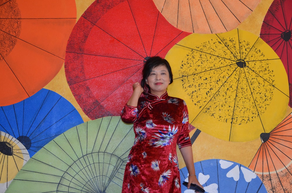 smiling woman wearing red and blue kimono dress standing near wall
