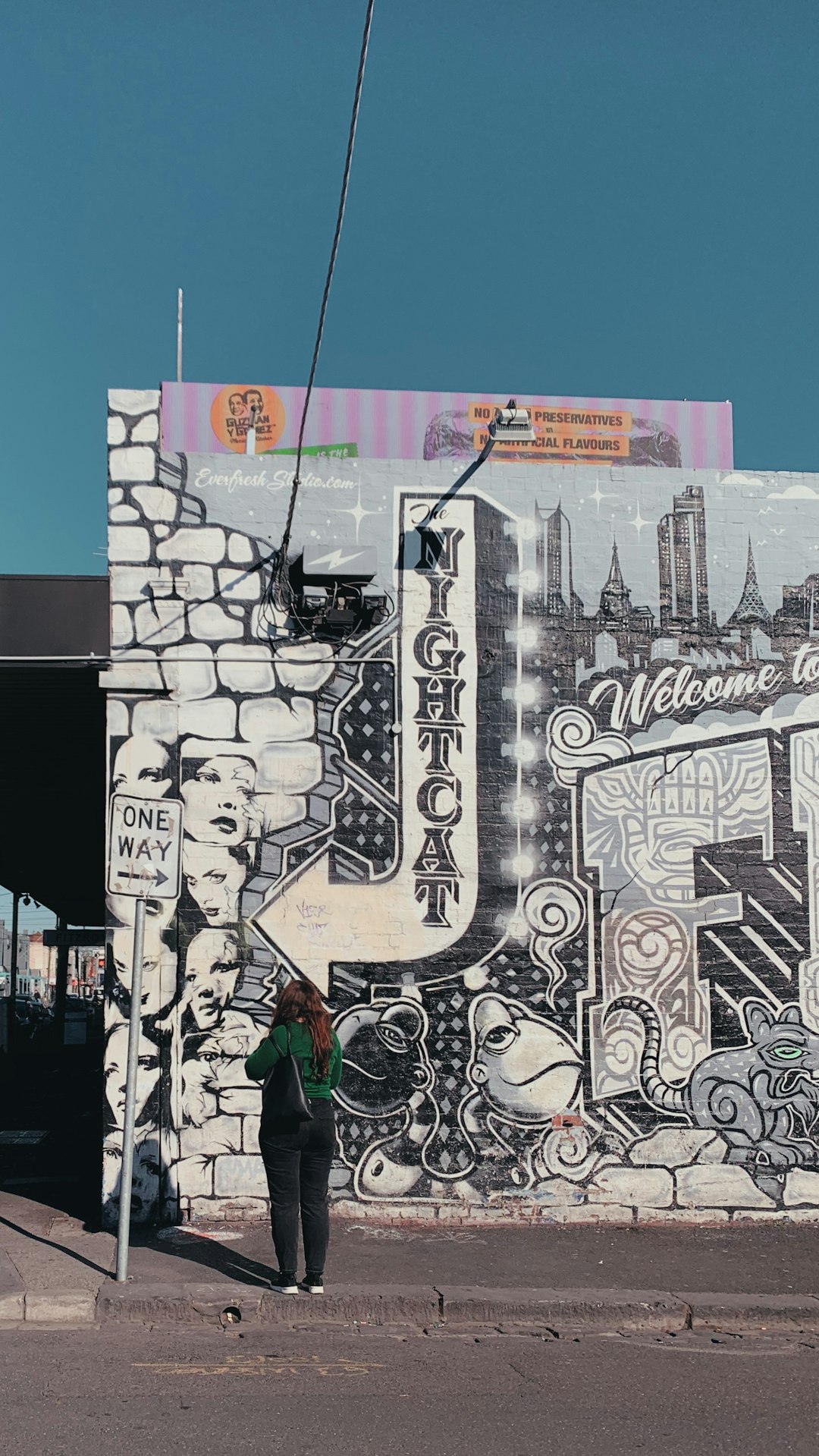 woman standing and facing on multicolored graffiti wall during daytime