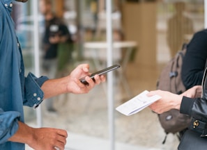 man holding smartphone in front of person in black leather jacket