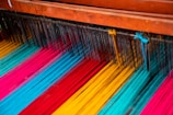 A loom in action with threads of natural colors.