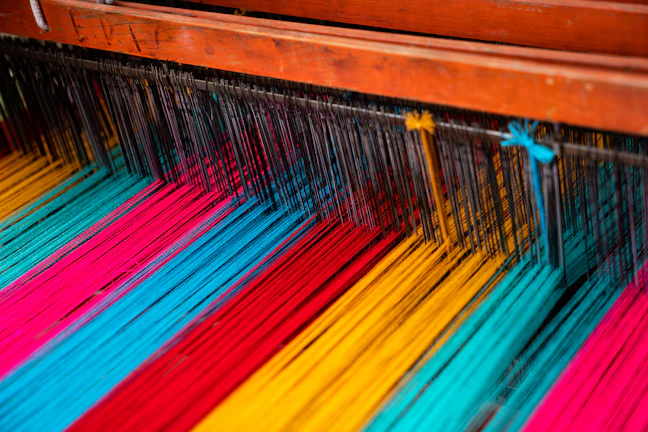 Close-up of colorful threads intertwined in a traditional loom.