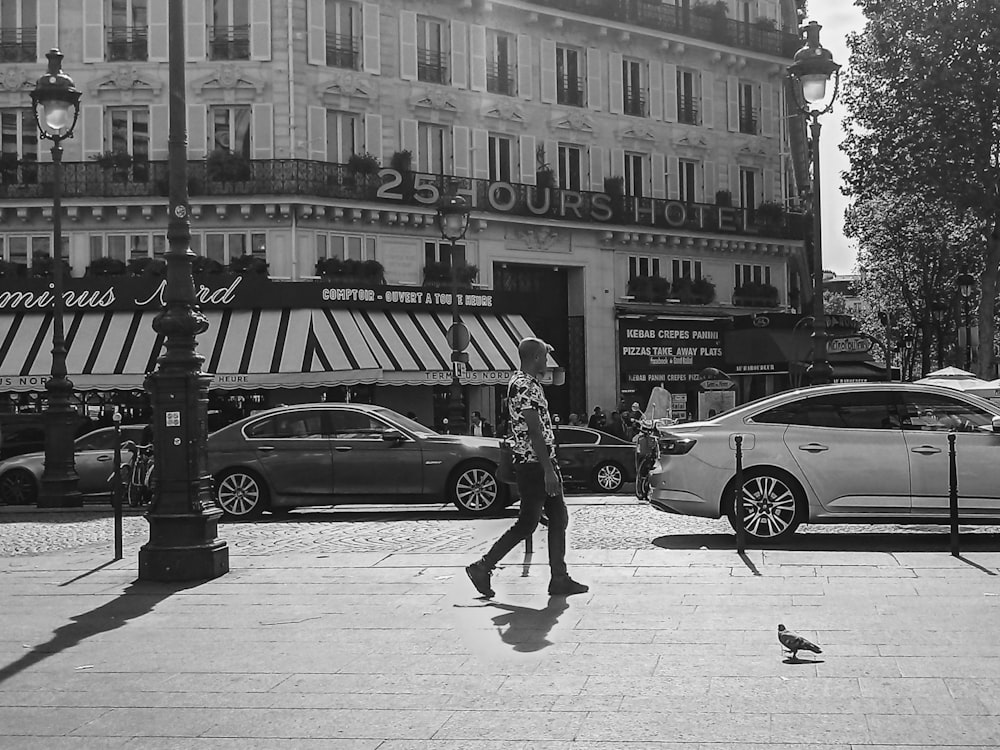 greyscale photography of man walking beside vehicles
