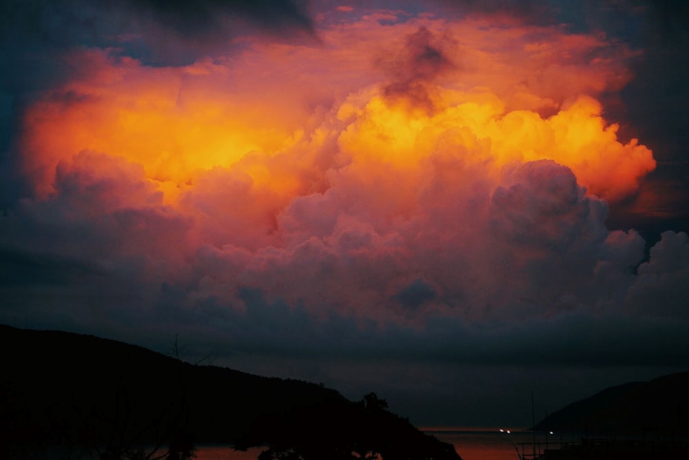 a large cloud is in the sky over a body of water