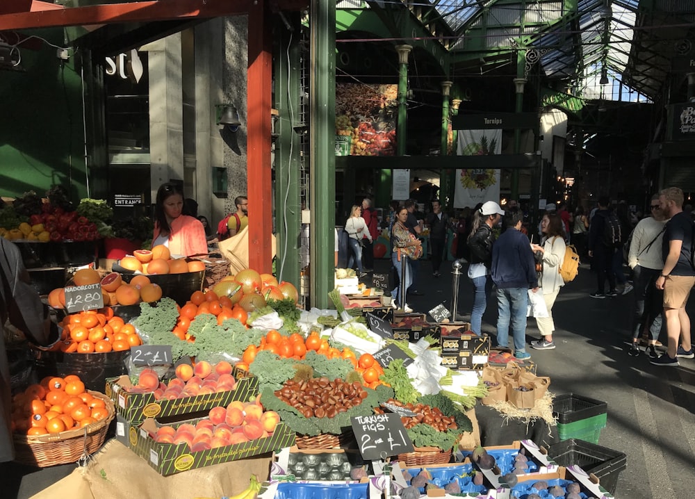 a group of people standing around a fruit stand