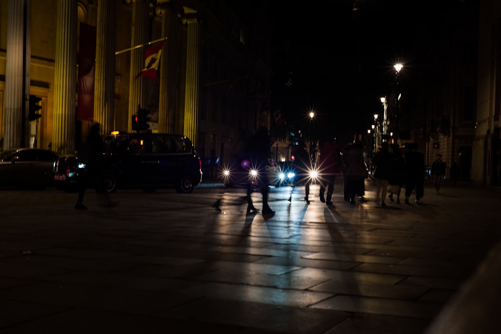 silhouette photography of people crossing a pedestrian lane during nighttime