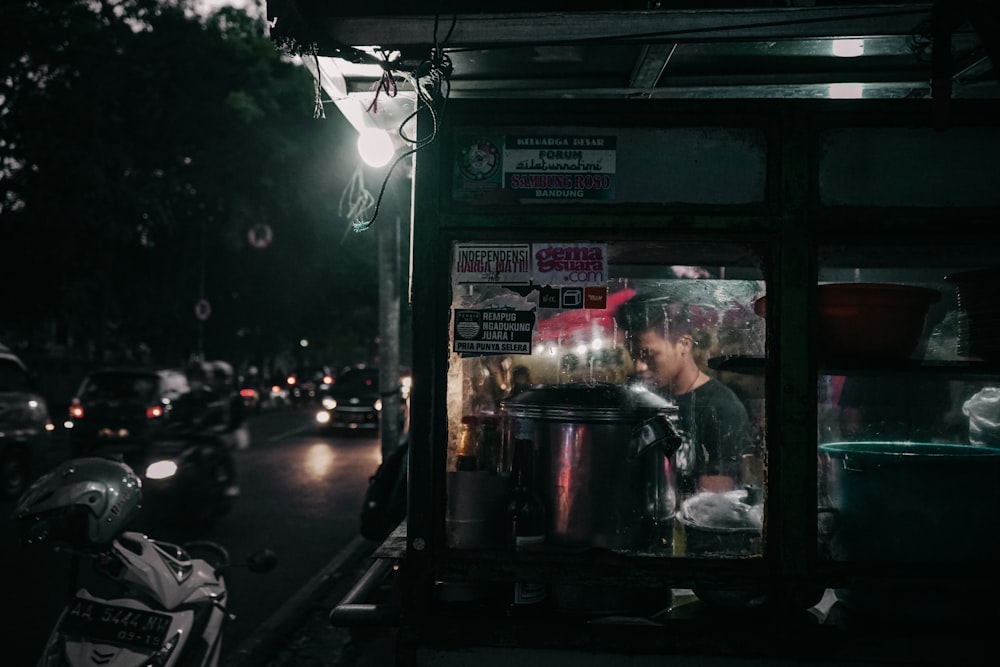 a man sitting at a food stand in the dark