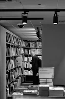 A person stands in a bookstore aisle, focused on shelves filled with various art books. The environment is well-lit with overhead lights and the books are organized neatly on the shelves.