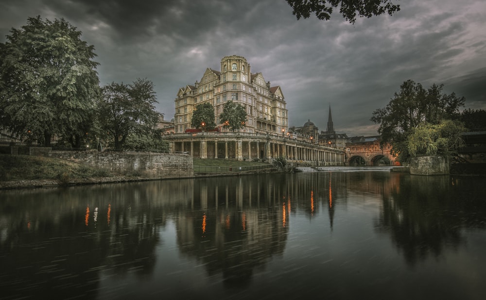 reflection of gray building on body of water during daytime