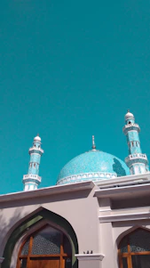 A vibrant photo of the Blue Mosque in Mazar-i-Sharif glowing under a clear blue sky.