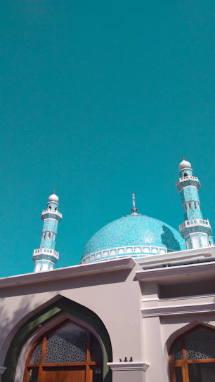 A vibrant photo of the Blue Mosque in Mazar-i-Sharif glowing under a clear blue sky.