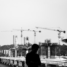 grayscale photography of man with a construction site in the background