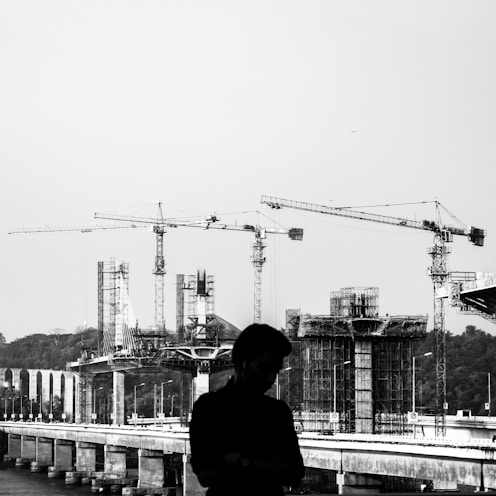 grayscale photography of man with a construction site in the background