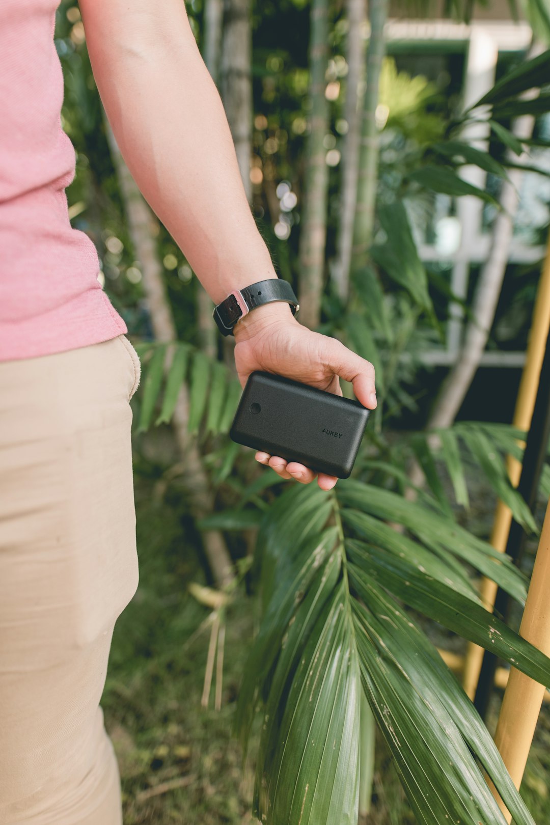 person holds black device near plants