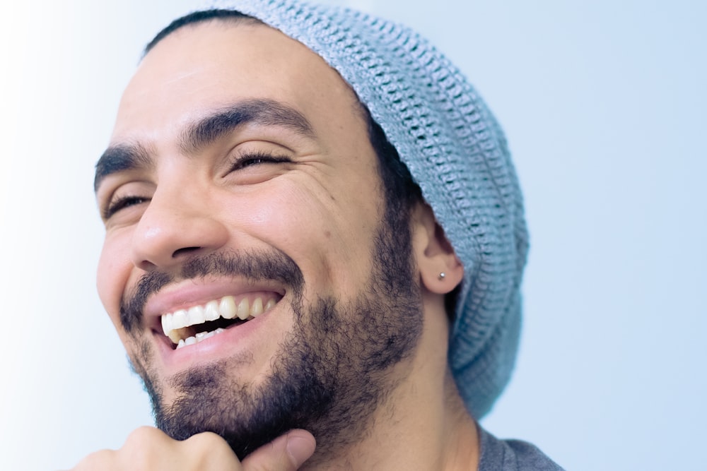 Homme souriant portant un bonnet en tricot turquoise