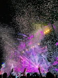 A vibrant concert crowd under colorful stage lights, hands raised in excitement.