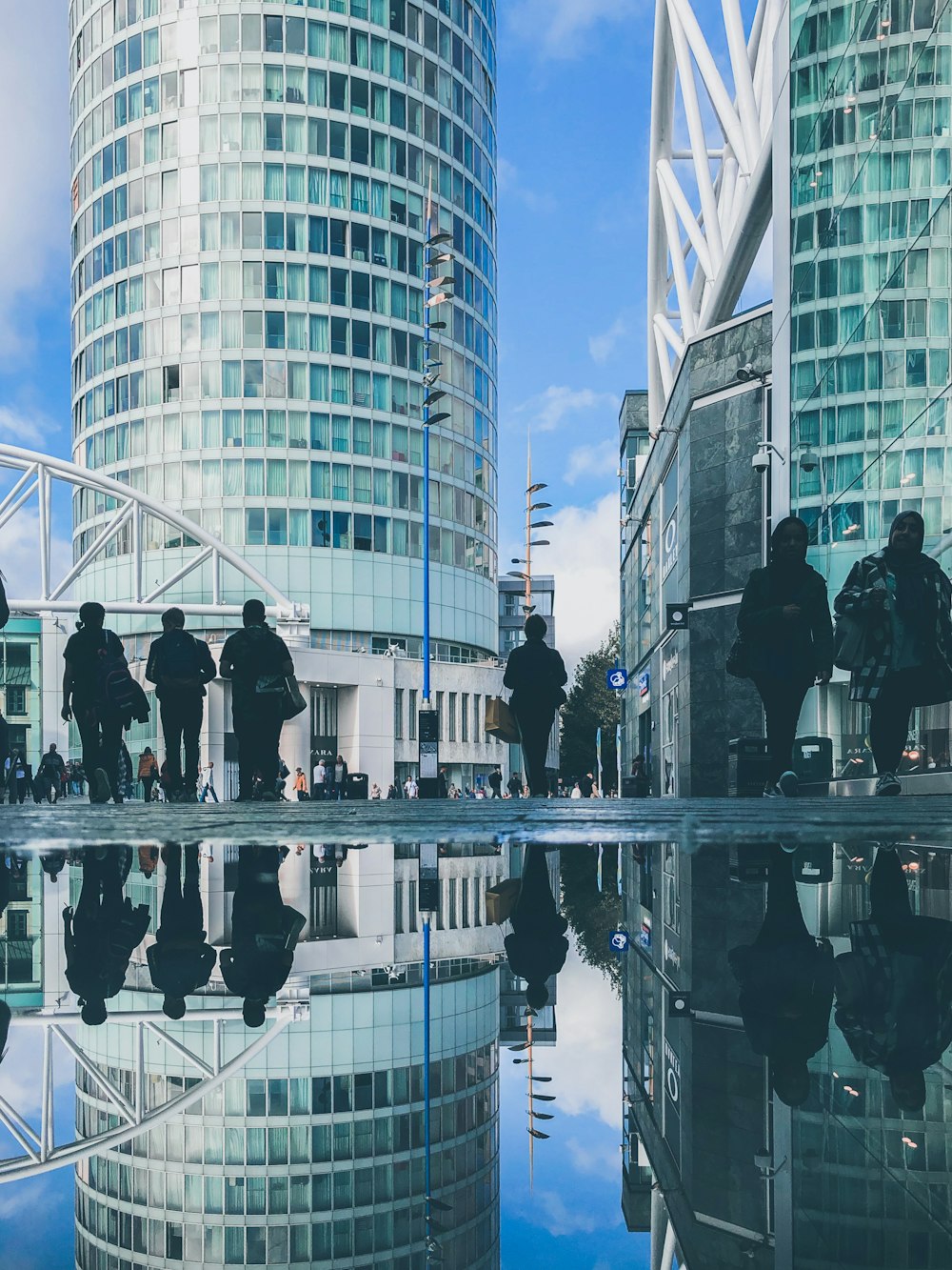 people walking beside a calm body of water and buildings at daytime