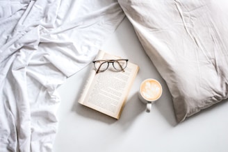 A serene scene of a woman enjoying coffee, wearing a softly illustrated t-shirt in a bright, airy room.
