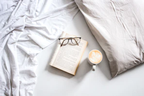 A cozy morning scene with a newspaper, glasses, and a cup of Noble Cup coffee on a windowsill.